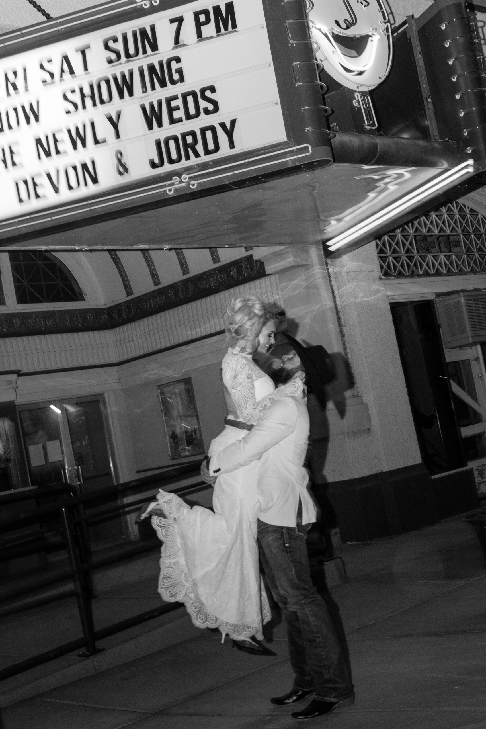 Bride and groom standing under the historic Luna Theater marquee in Clayton, New Mexico.