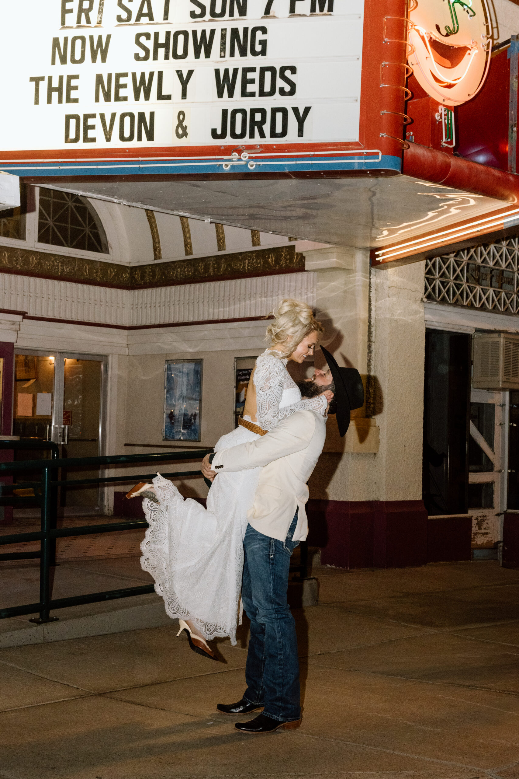 Bride and groom standing under the historic Luna Theater marquee in Clayton, New Mexico.