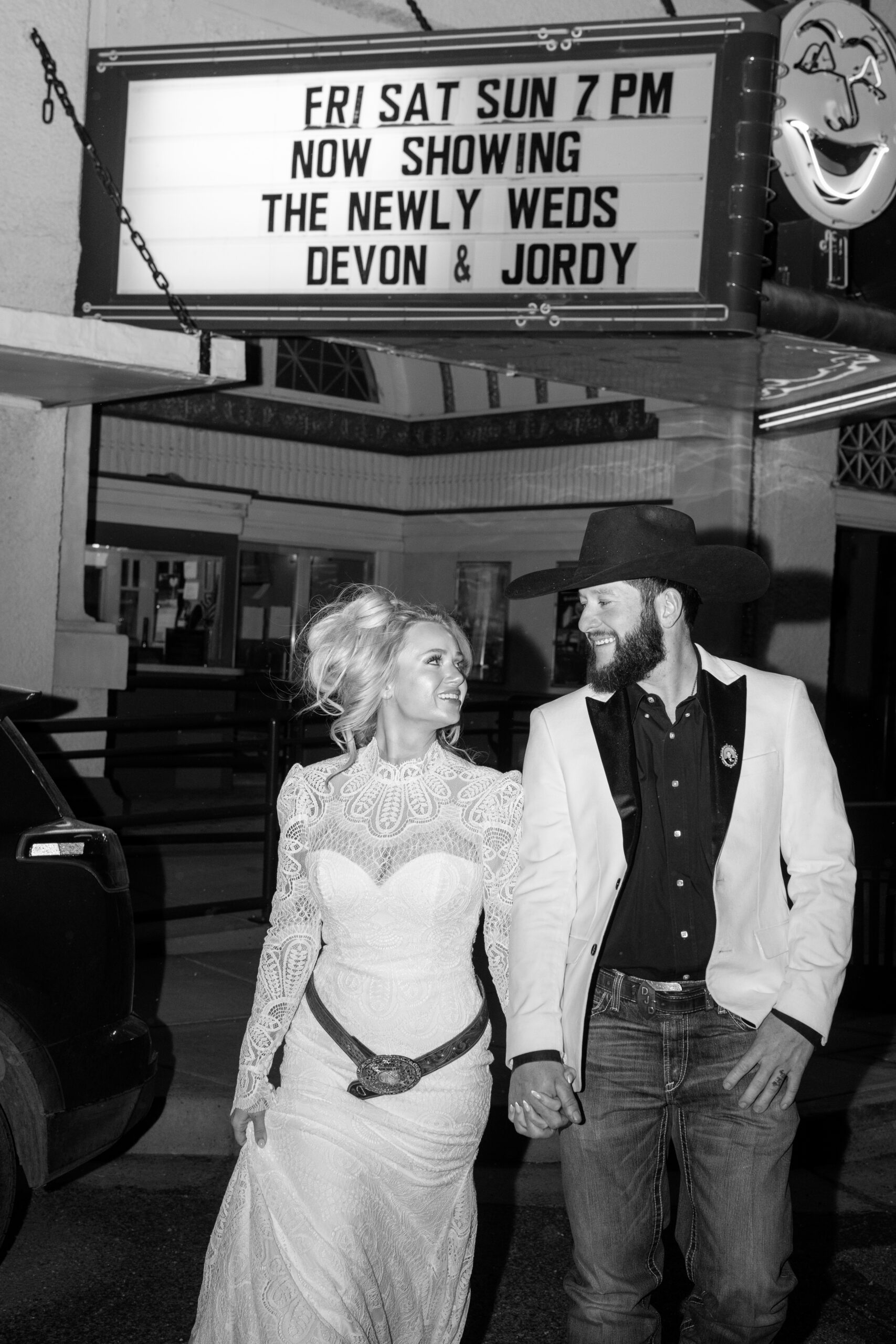 Bride and groom standing under the historic Luna Theater marquee in Clayton, New Mexico.