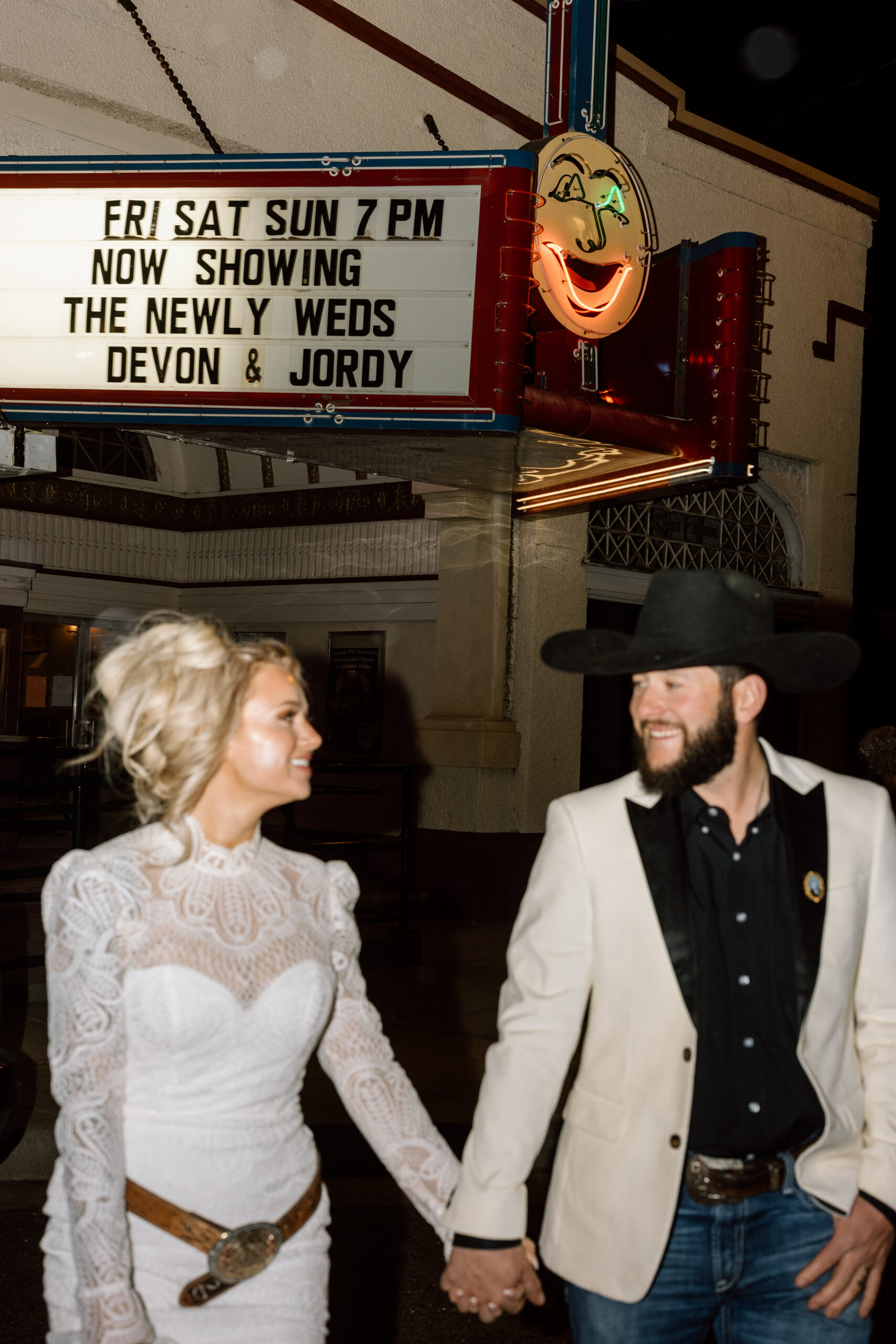 Bride and groom standing under the historic Luna Theater marquee in Clayton, New Mexico.