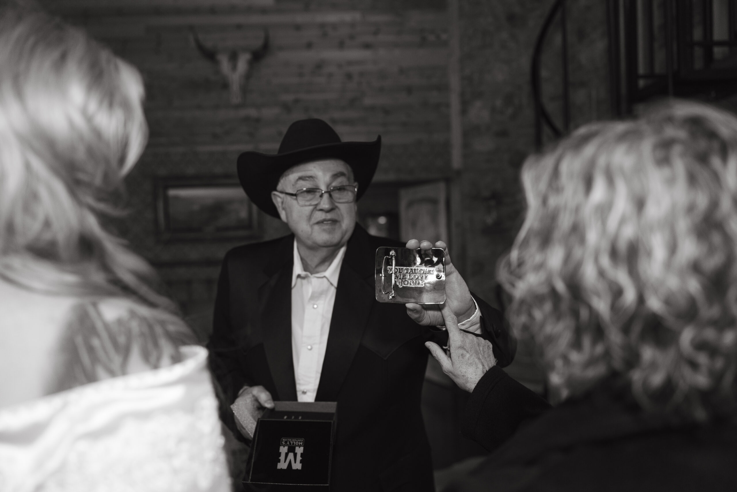 Close-up of a custom engraved silver belt buckle gift for a father of the bride at a Texas elopement.