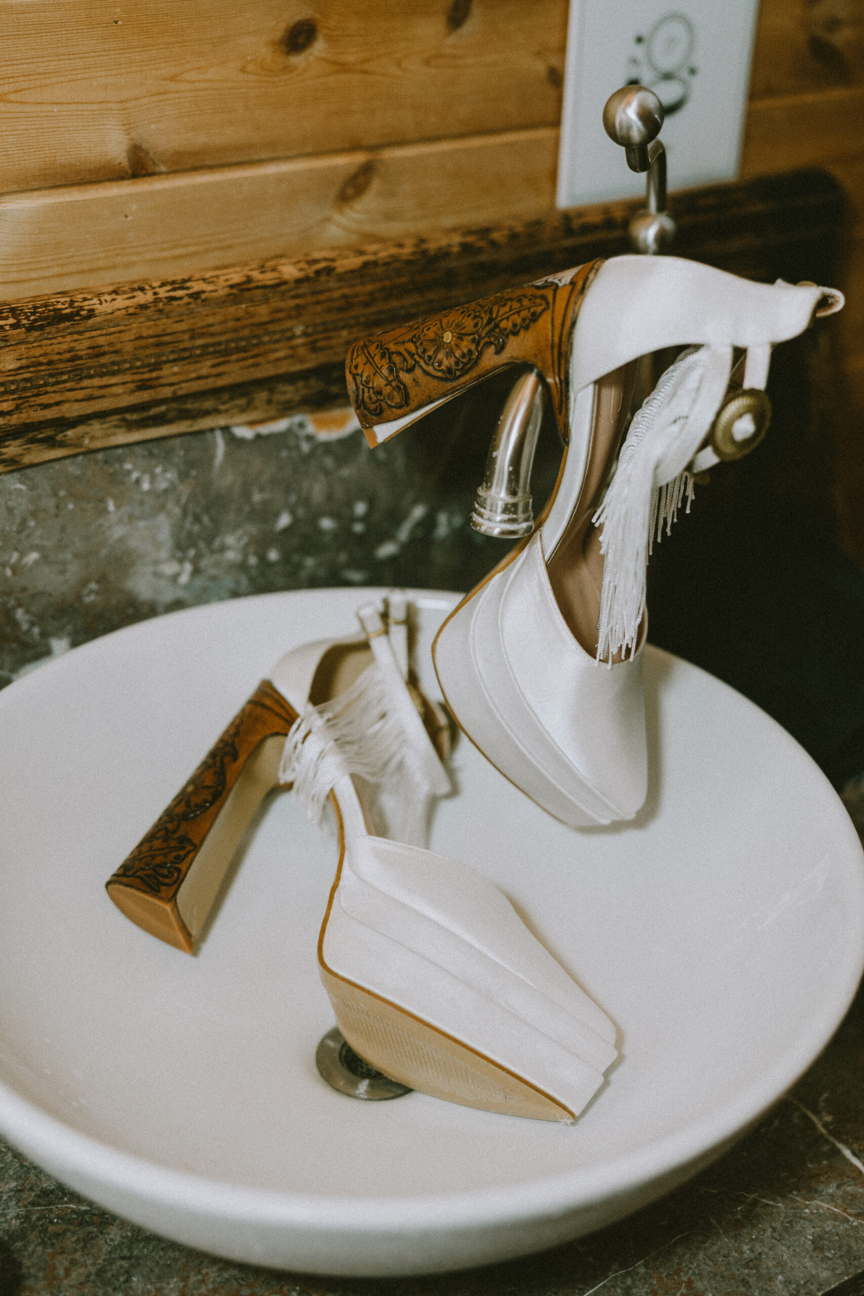 White Western elopement heels with fringe and custom engraved wood-tooled heel details.