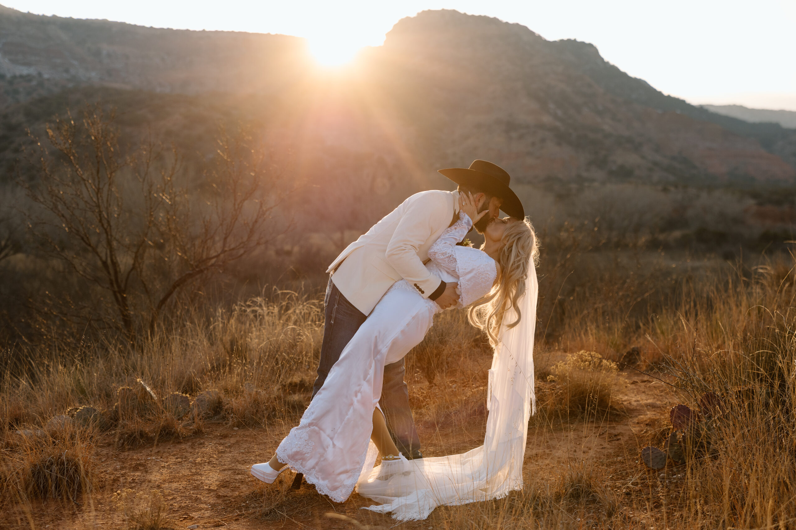 Romantic sunset elopement photo of a couple kissing in the desert landscape of Palo Duro Canyon, Texas.