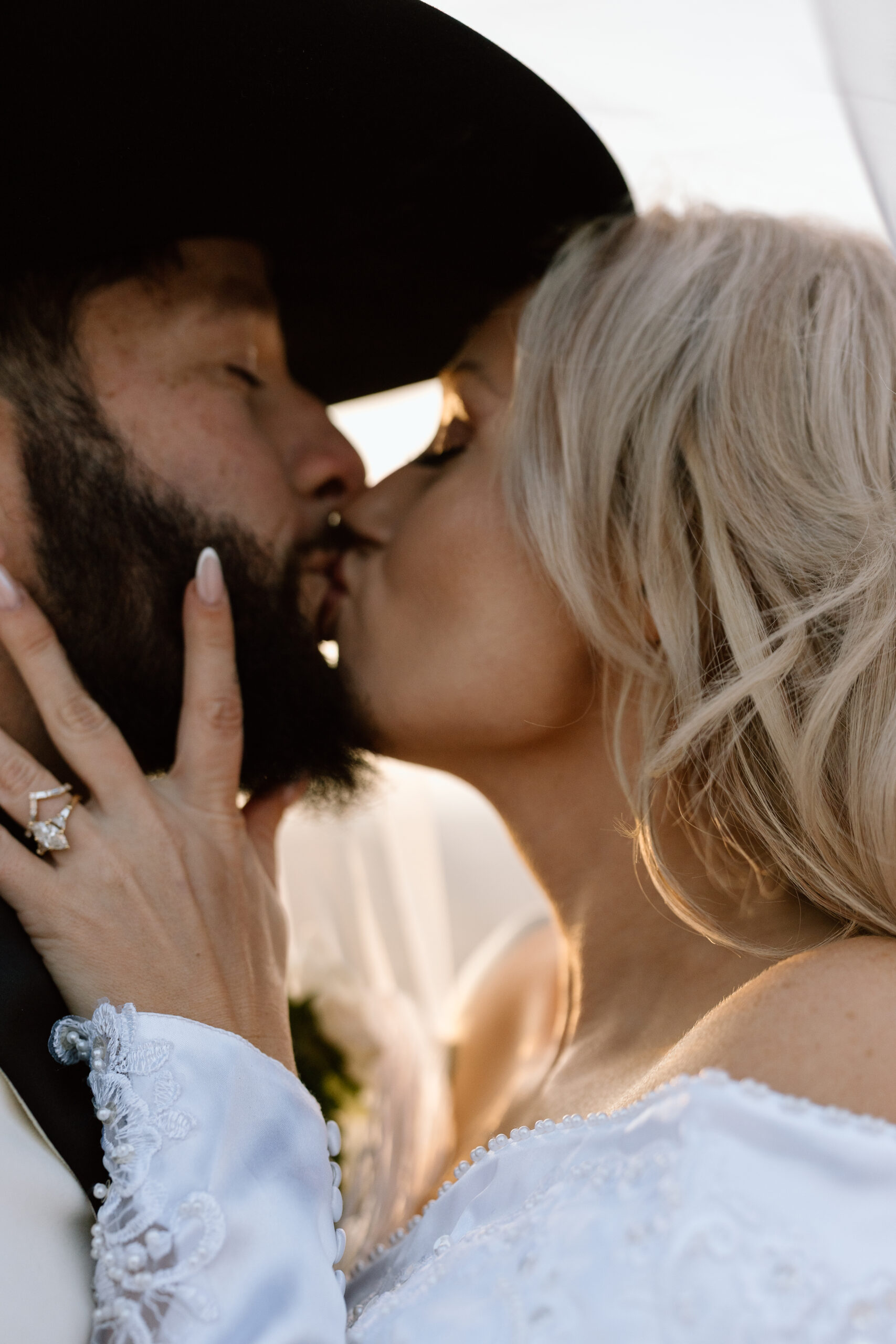 Close-up of a bride and groom kissing, featuring a fringe wedding veil and Western wedding style.