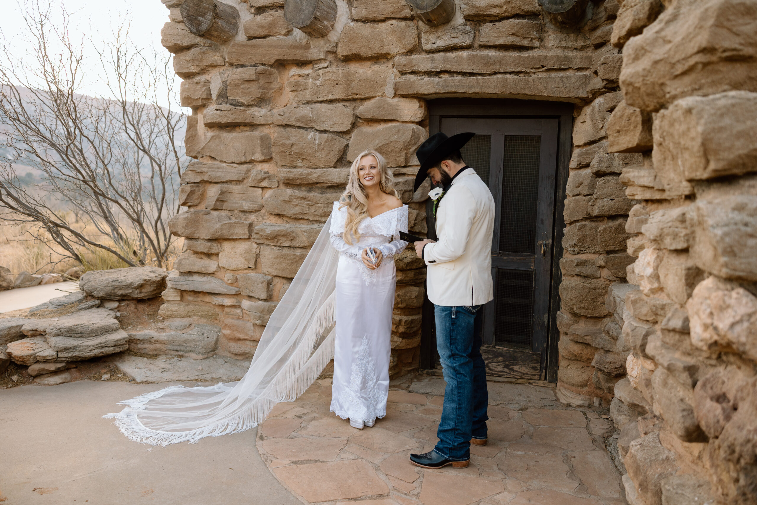 Bride in a fringe cathedral veil and groom in a white tuxedo jacket at Palo Duro Canyon State Park.