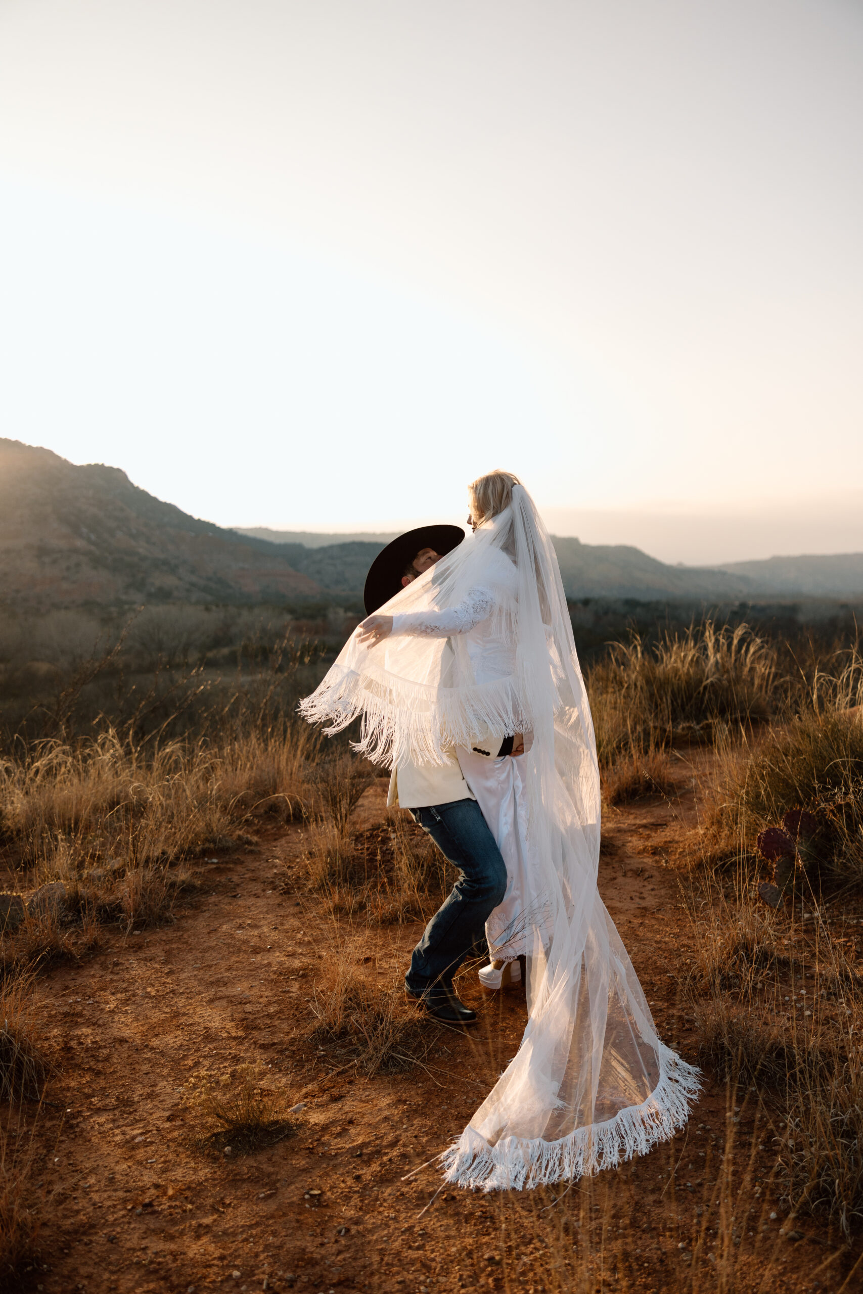 Close-up of a bride and groom featuring a fringe wedding veil and Western wedding style.