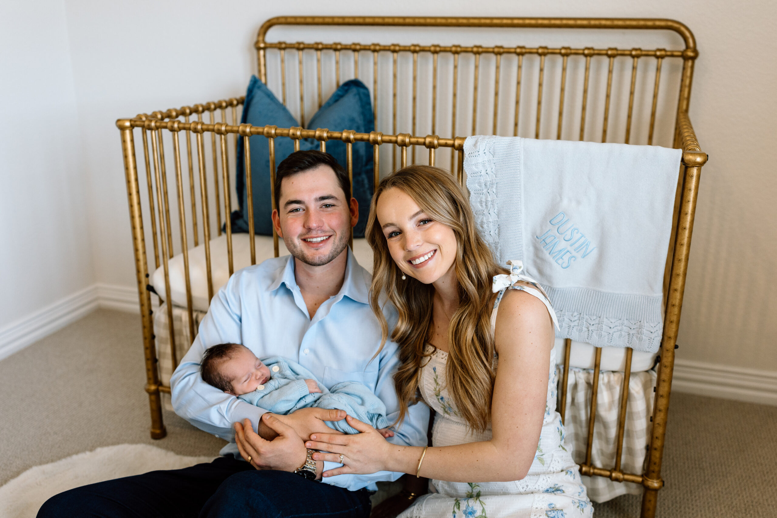 Parents cuddle their new baby during an intimate in-home photo session, featuring our lifestyle newborn photography tips.