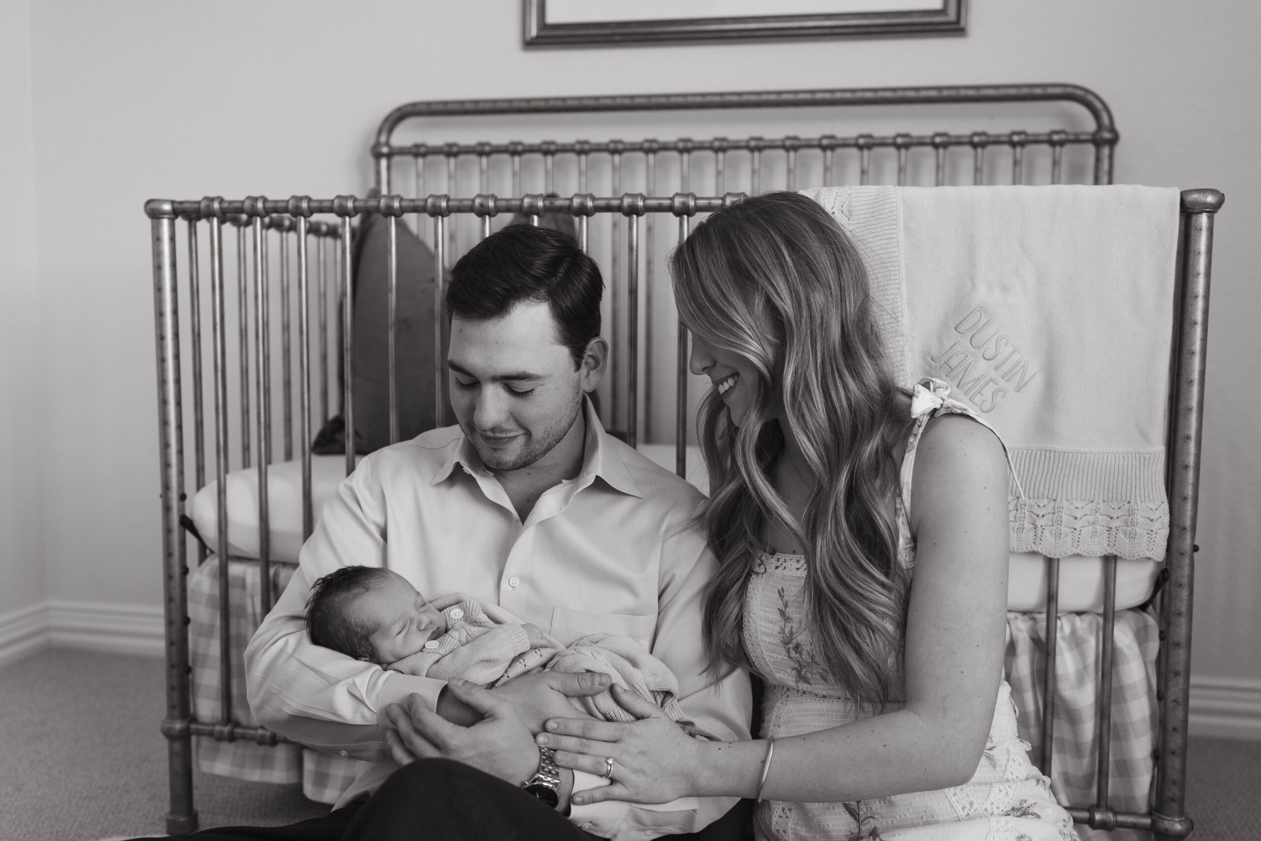 Parents cuddle their new baby during an intimate in-home photo session, featuring our lifestyle newborn photography tips.
