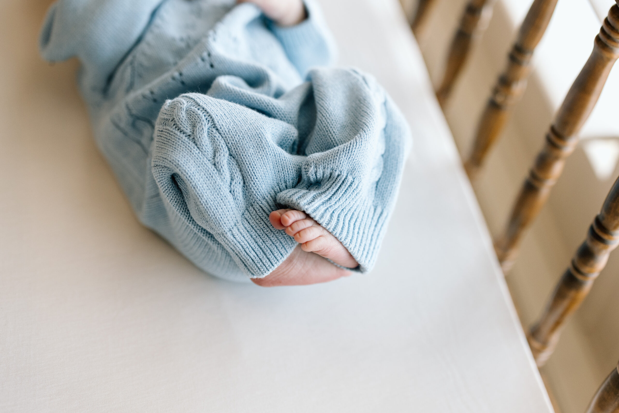 Lifestyle newborn photography tips featuring a baby in a blue knit romper.