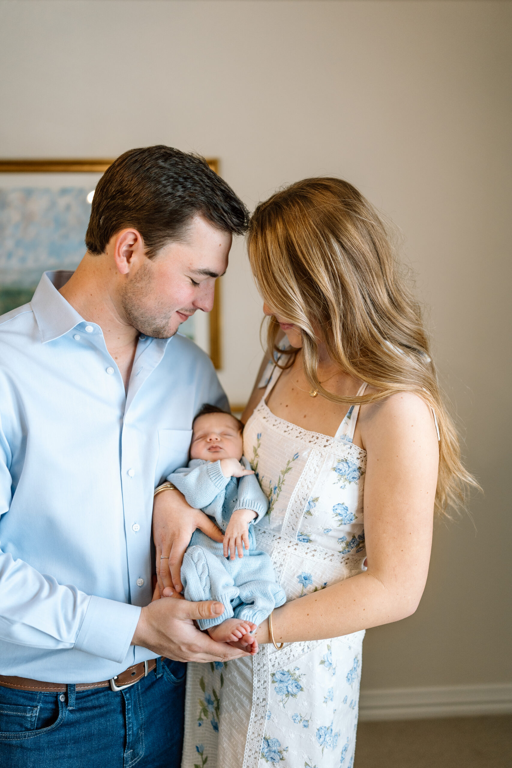 Parents cuddle their new baby during an intimate in-home photo session, featuring our lifestyle newborn photography tips.