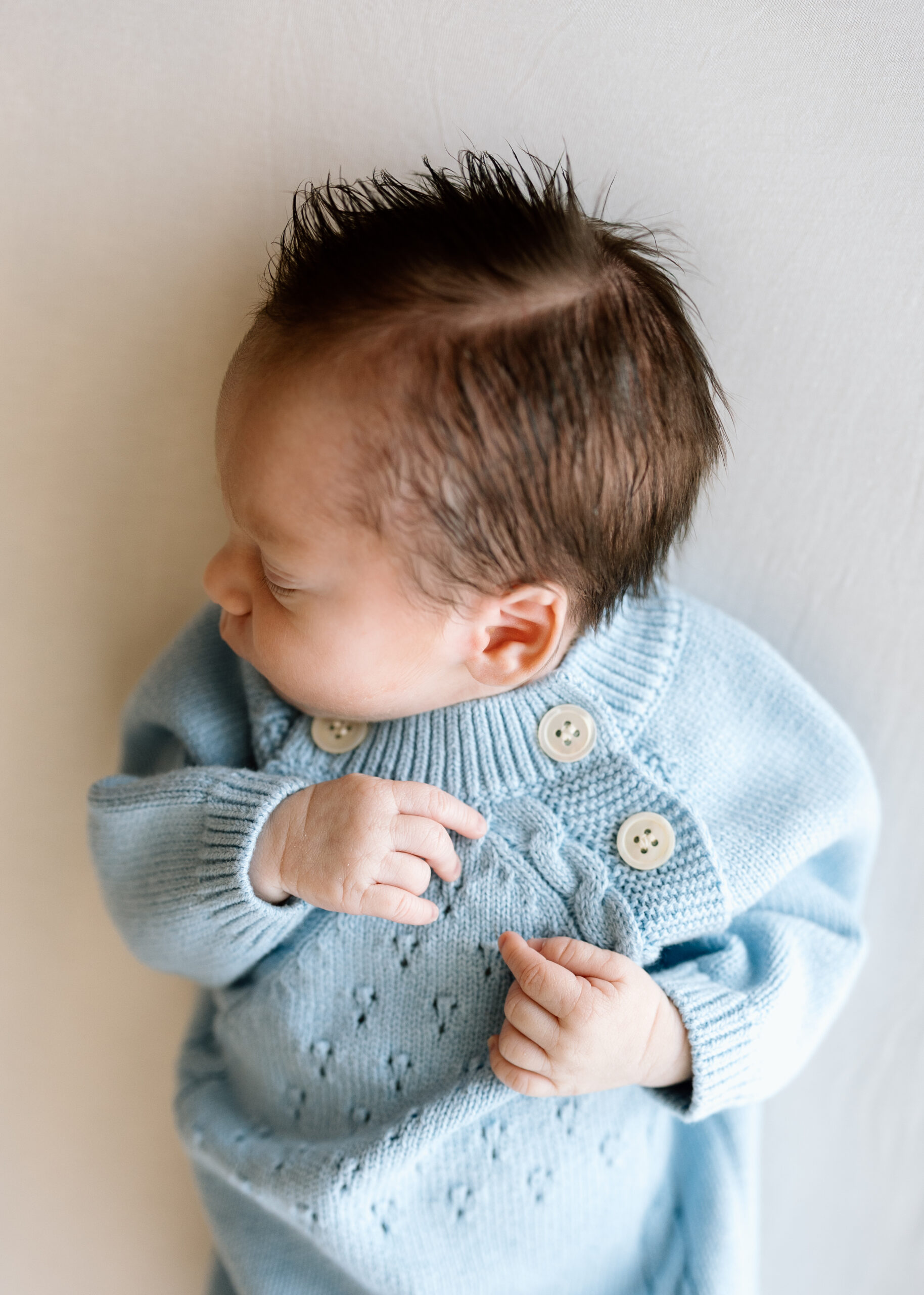 Lifestyle newborn photography tips featuring a baby in a blue knit romper.
