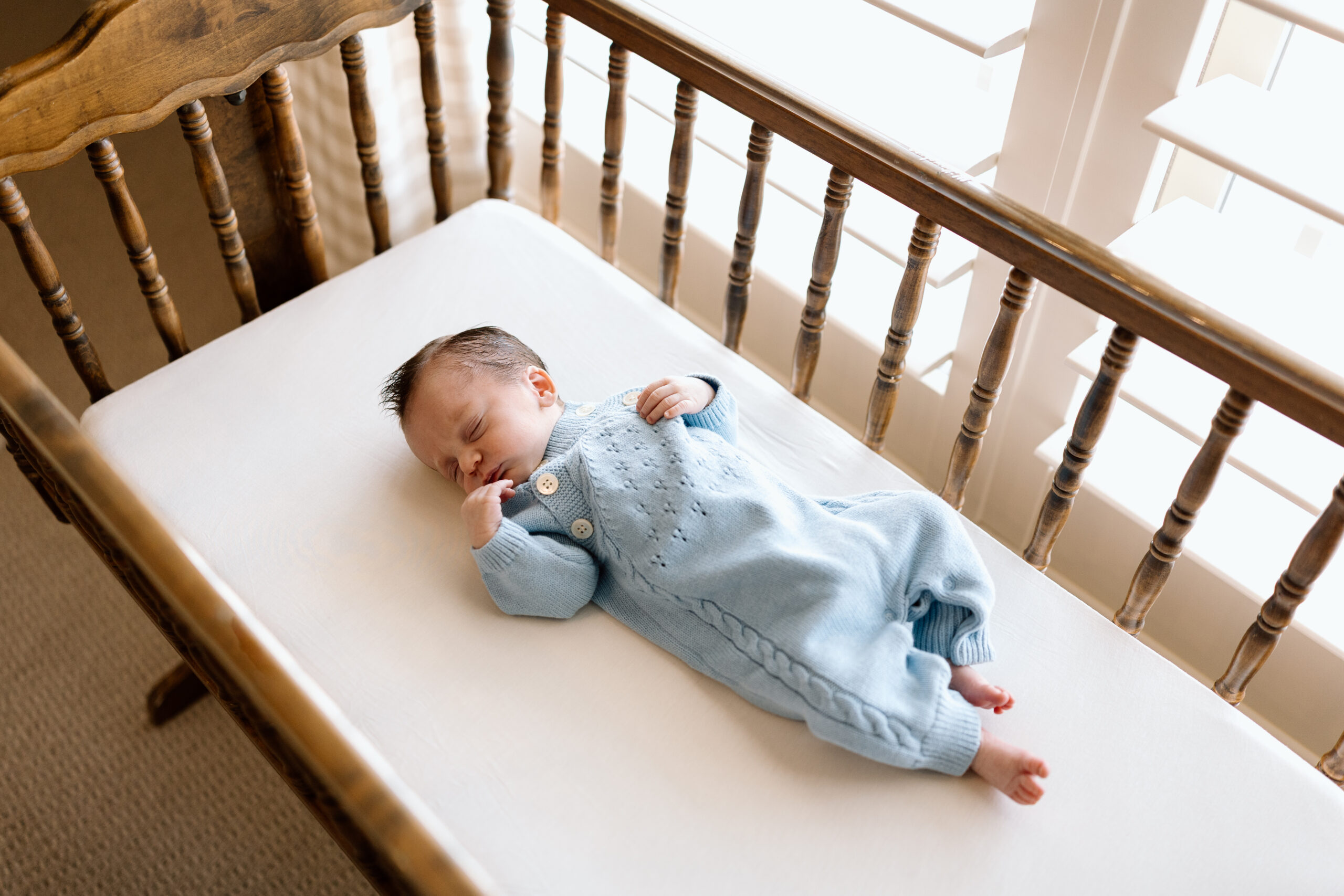 Lifestyle newborn photography tips featuring a baby in a blue knit romper.
