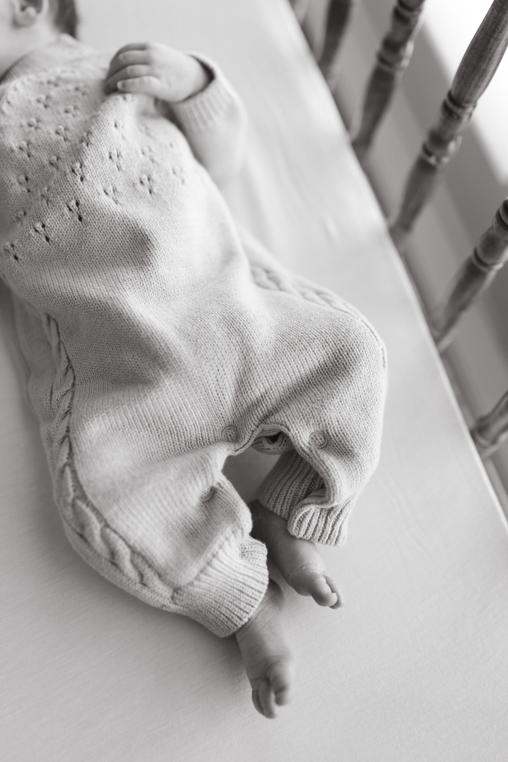 A baby boy sleeps peacefully in a crib during an at-home session, following our best lifestyle newborn photography tips