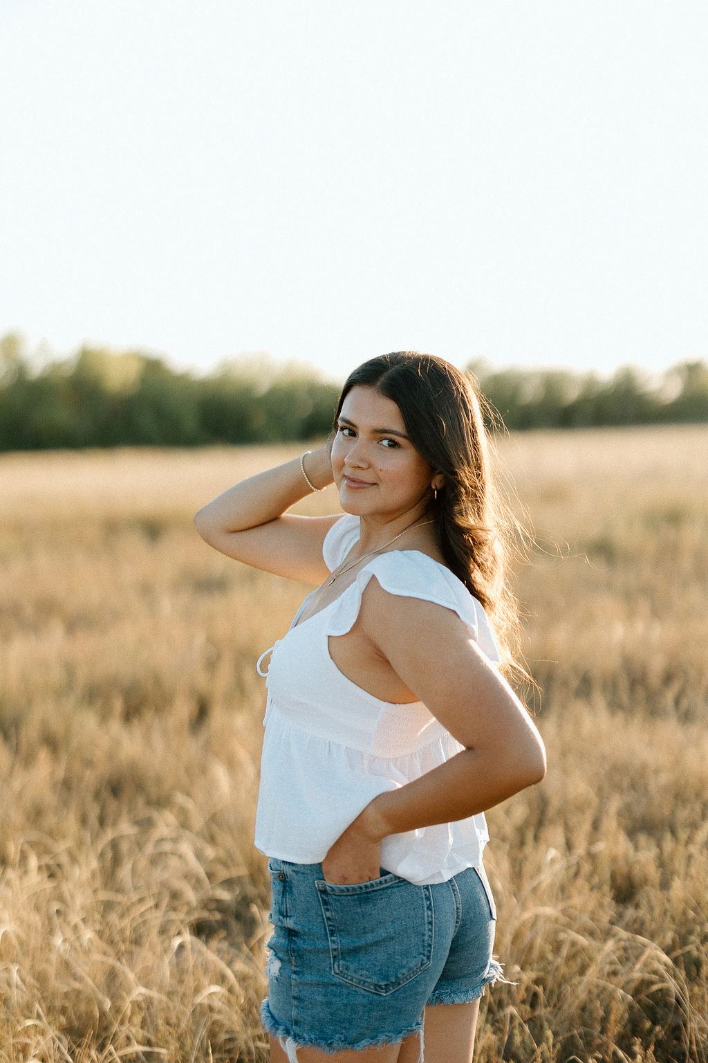 Sun-drenched Texas Panhandle senior portraits in a golden field near Canyon, capturing the warm glow of a West Texas sunset.