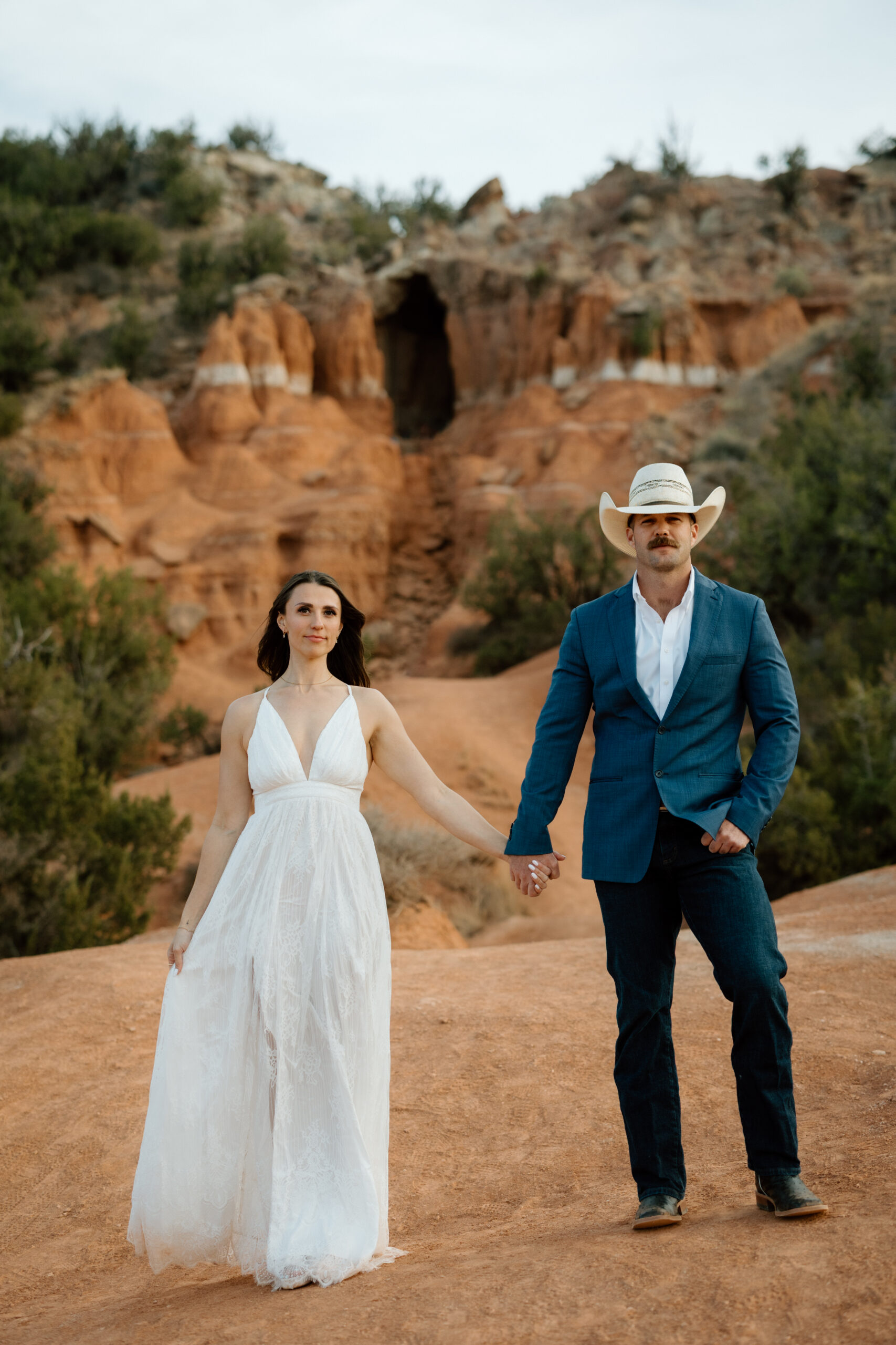 Engaged couple in Palo Duro Canyon with groom in western attire and bride in white dress