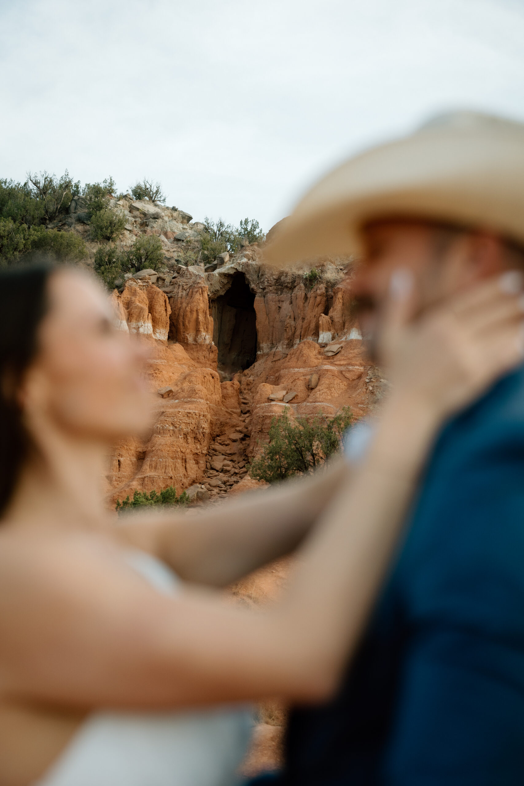 Engaged couple in Palo Duro Canyon with groom in western attire and bride in white dress