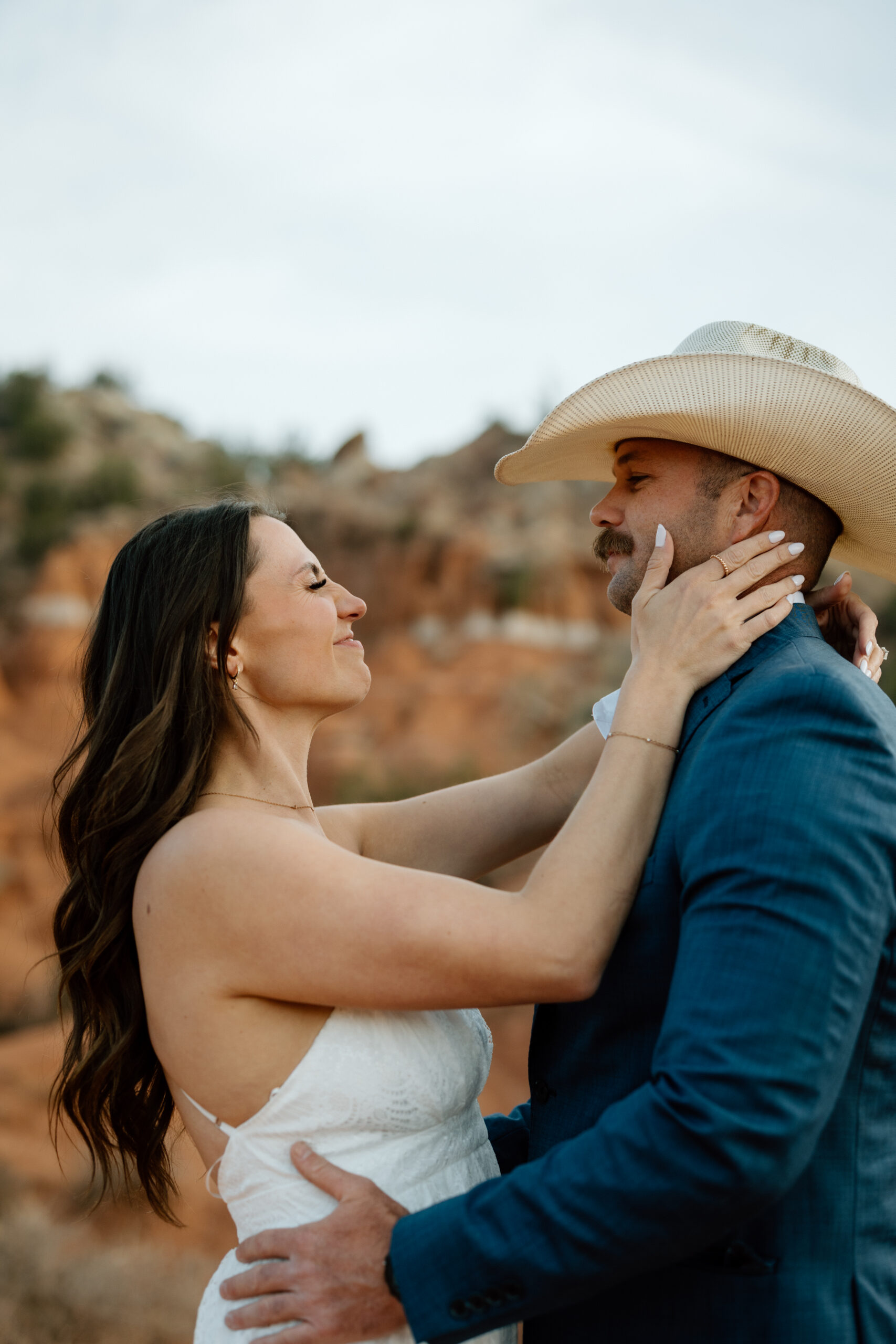 Engaged couple in Palo Duro Canyon with groom in western attire and bride in white dress