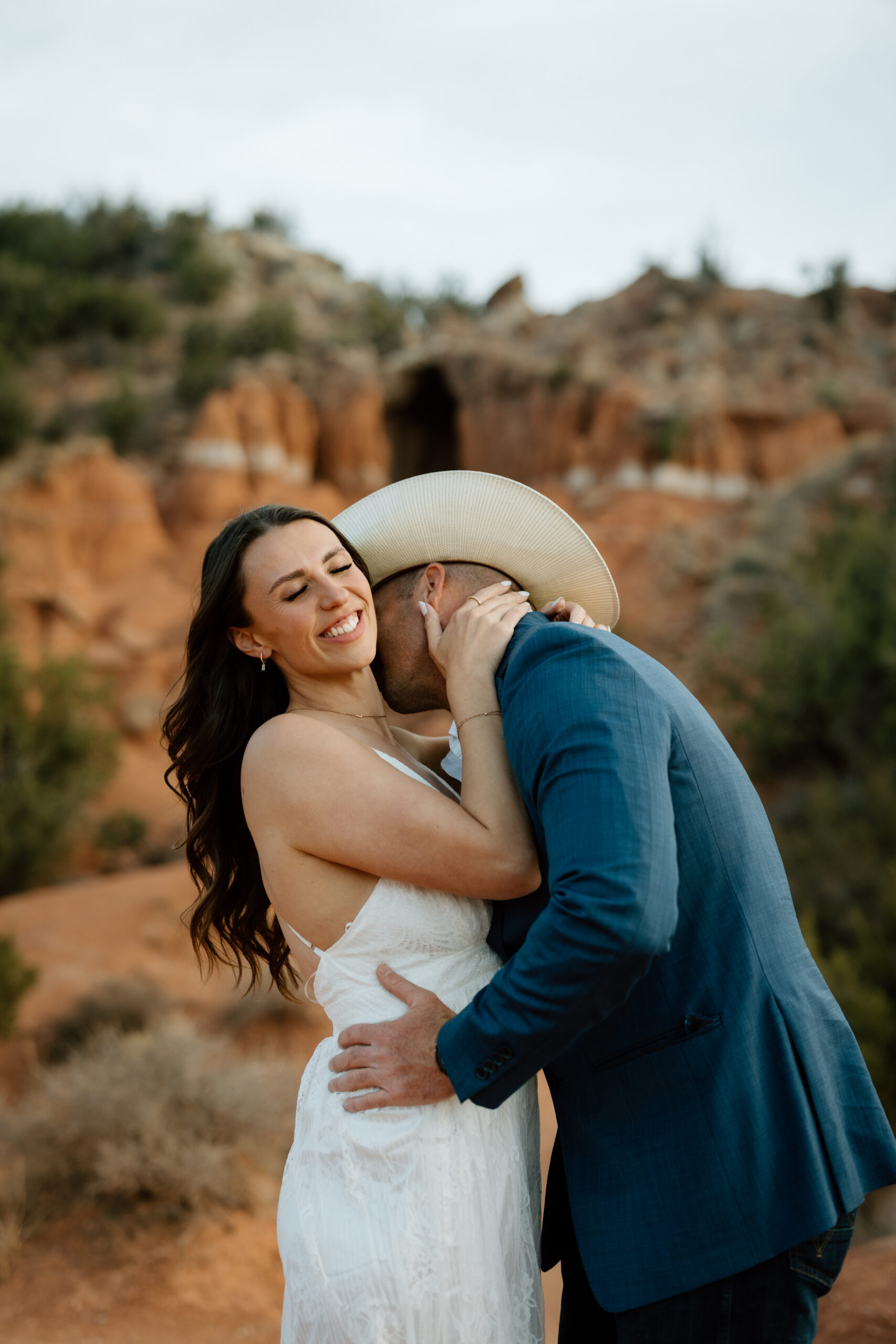 Engaged couple in Palo Duro Canyon with groom in western attire and bride in white dress